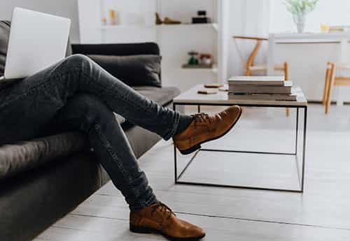 photo of a persons legs and feet as the recline on a couch with a laptop in the living room of a modern home
